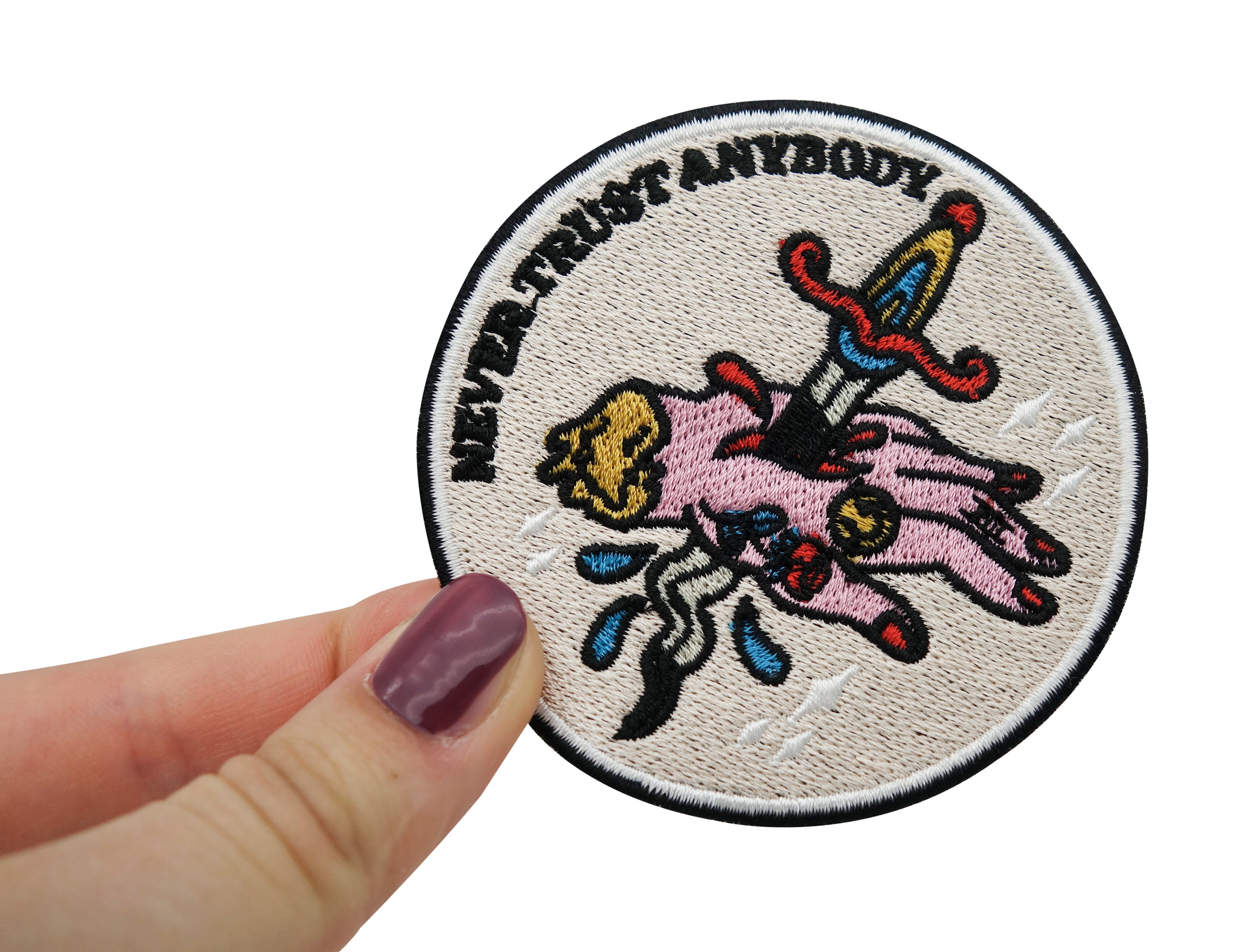 Frauenhand hält den Never Trust Anybody Patch