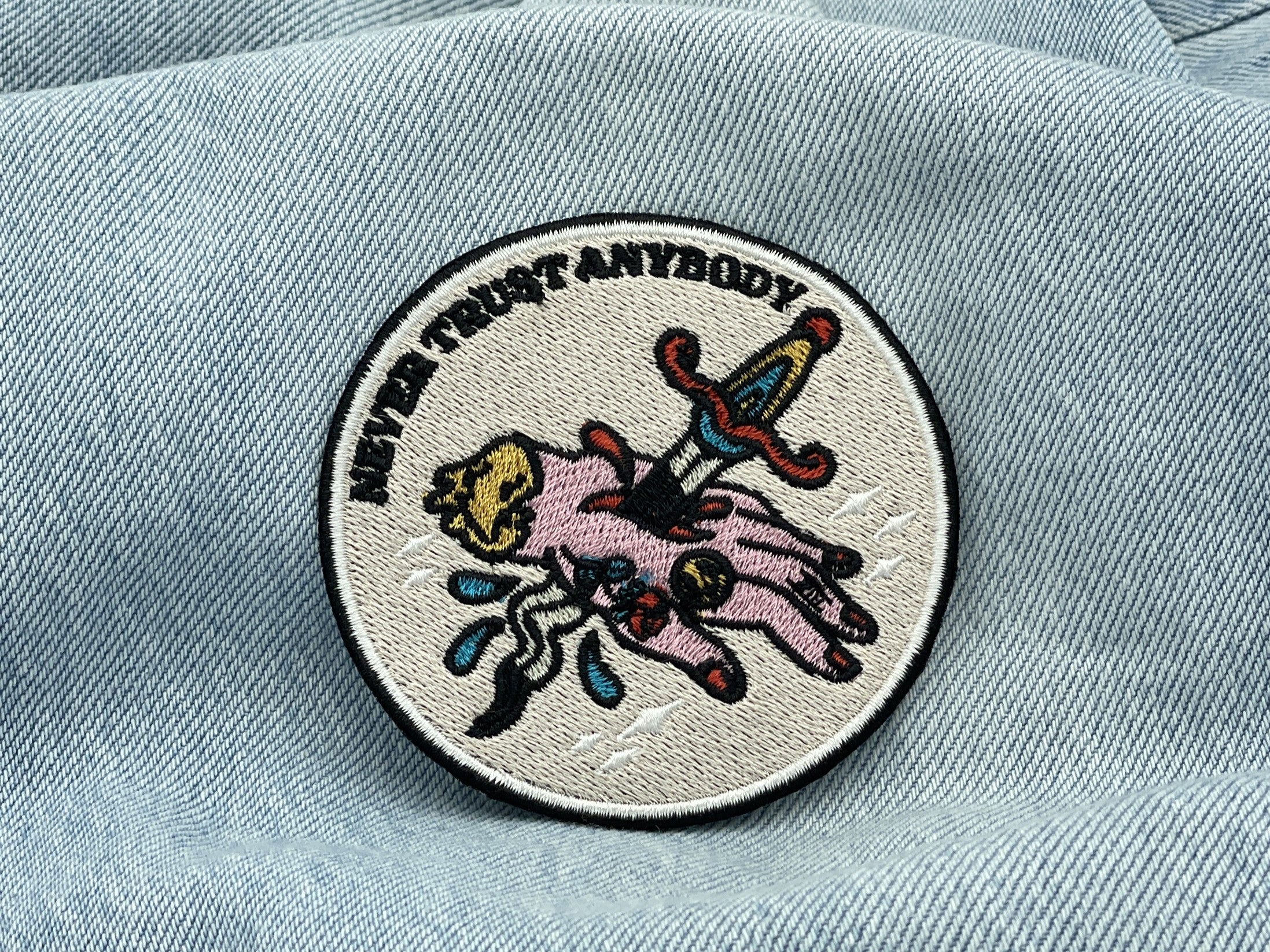 Never Trust Anybody Patch auf heller blauer Jeans