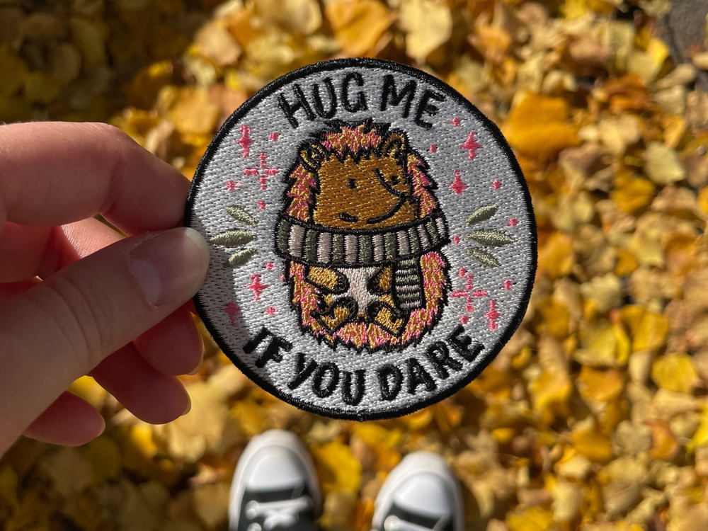 Frauenhand hält den Igel Patch vor herbstlichem Hintergrund