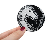Frauenhand hält den Pferdeköpfe Patch