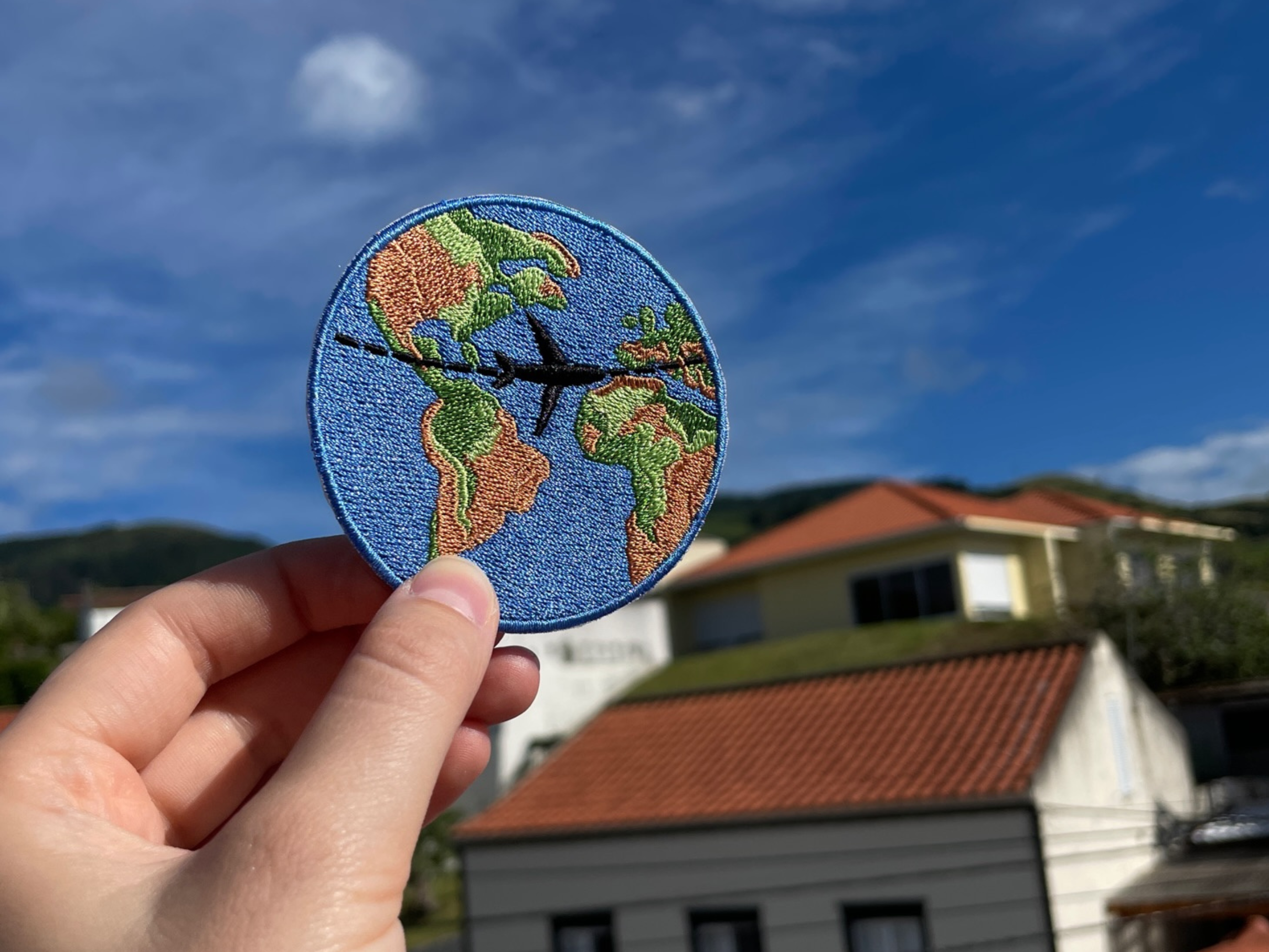 Weltreise Patch gehalten von einer Hand im Freien