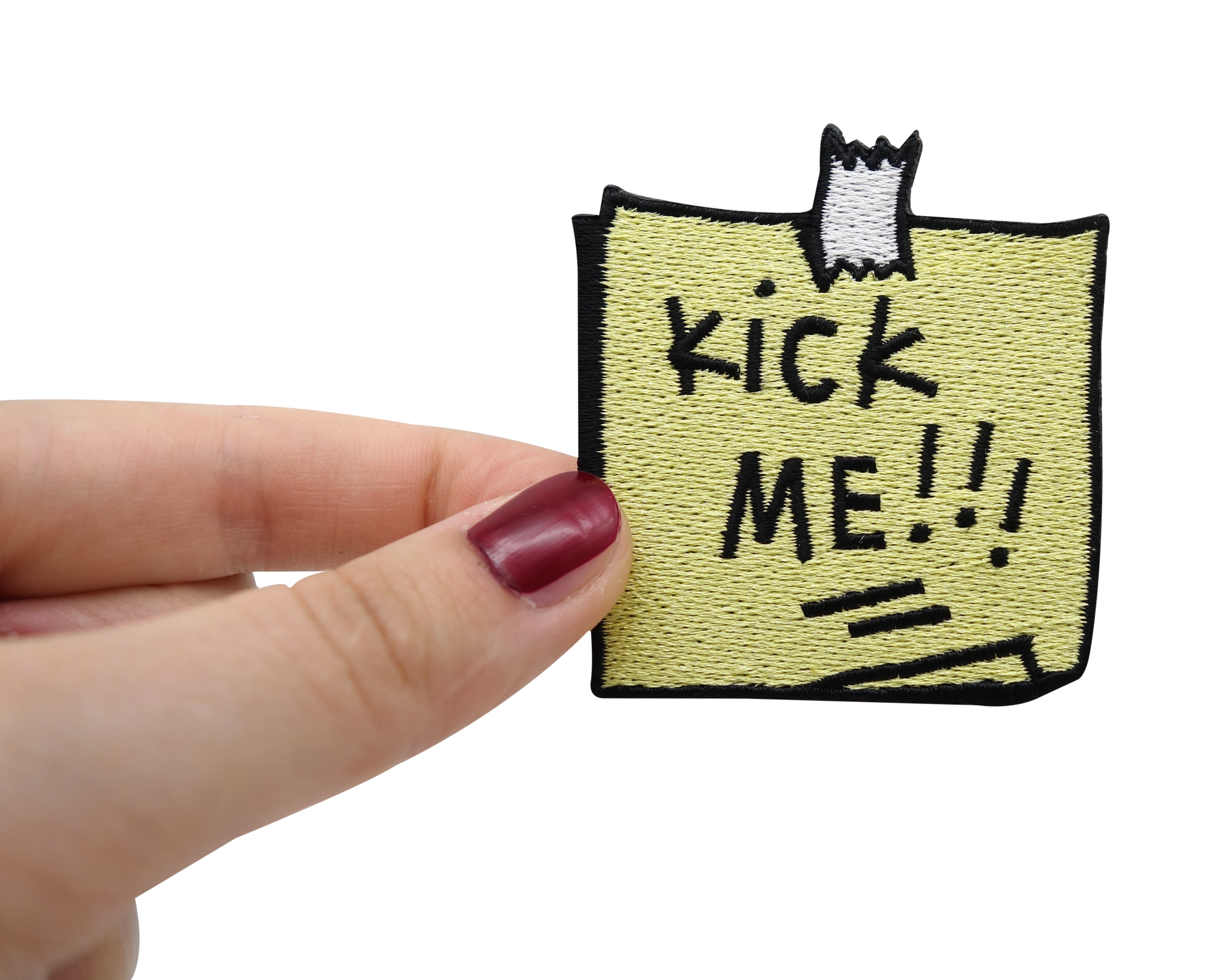 Frauenhand hält den Kick Me Notiz Patch