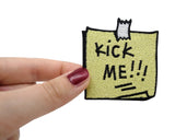 Frauenhand hält den Kick Me Notiz Patch