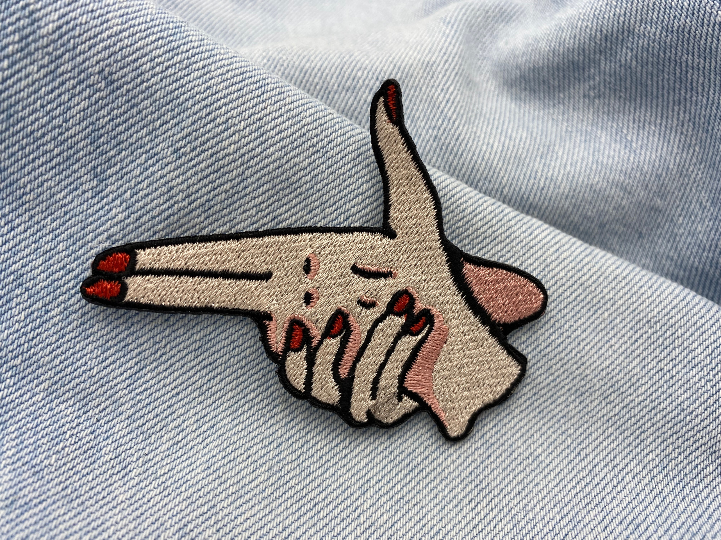Fingerpistole Patch auf hellblauer Jeans