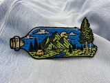Landschaft in Flasche Patch auf hellblauer Jeans