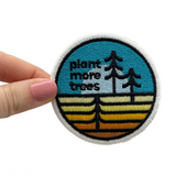 Frauenhand hält den Plant more Trees Patch 