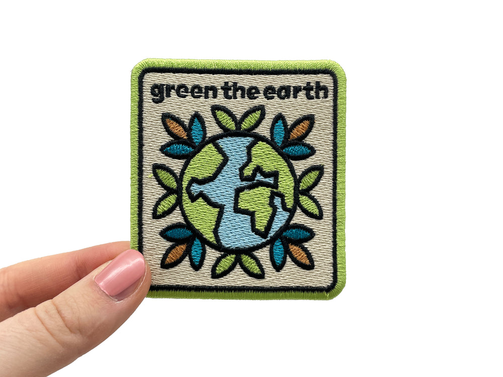 Frauenhand hält den Green the Earth Patch