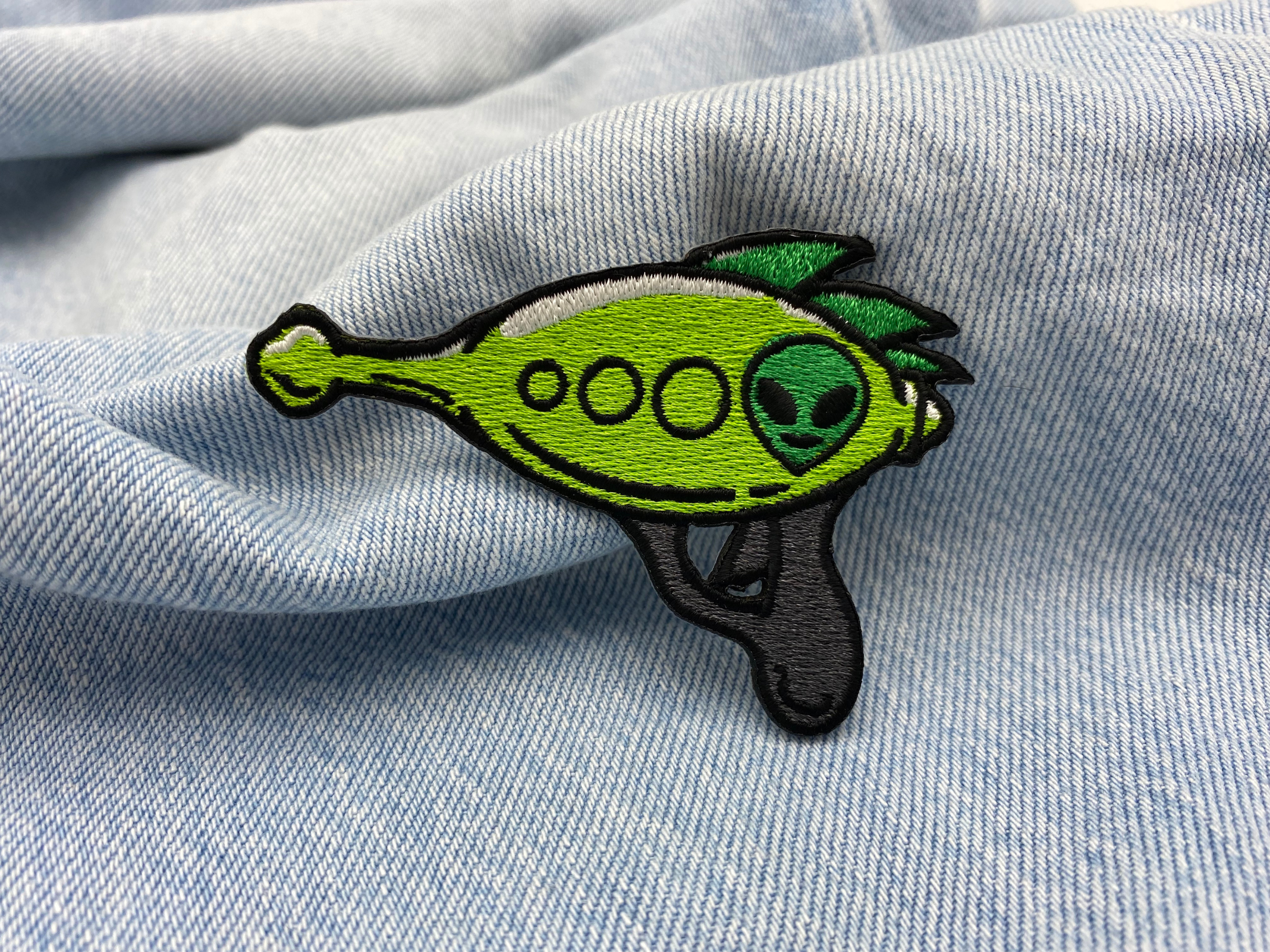 Alien Pistole Patch auf hellblauer Jeans