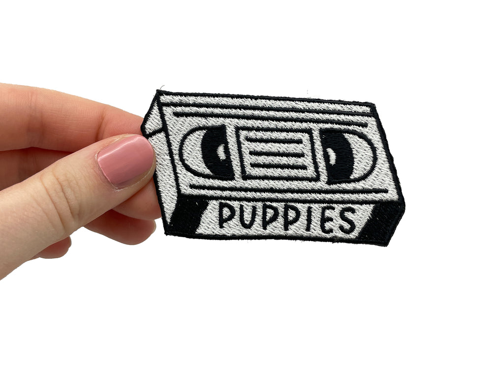 Frauenhand hält den Puppies Kassetten Patch