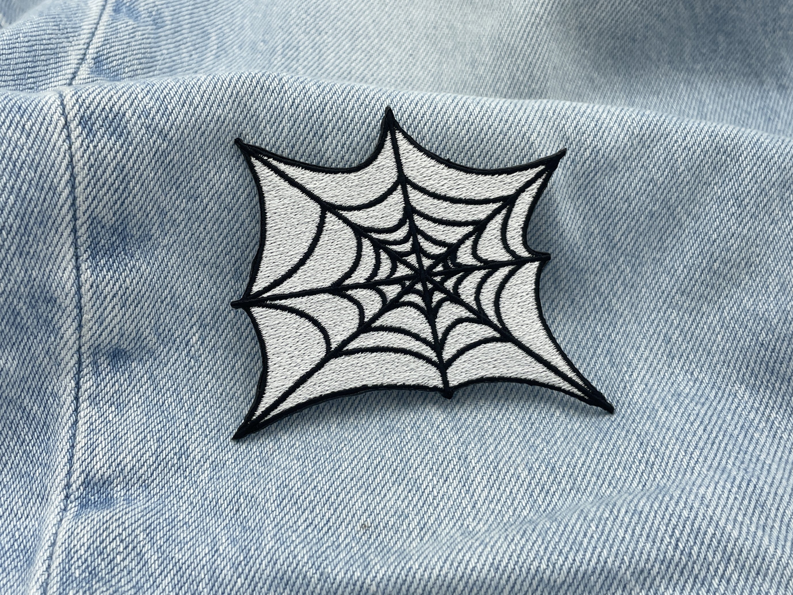 Spinnennetz Patch auf einer hellblauen Jeans