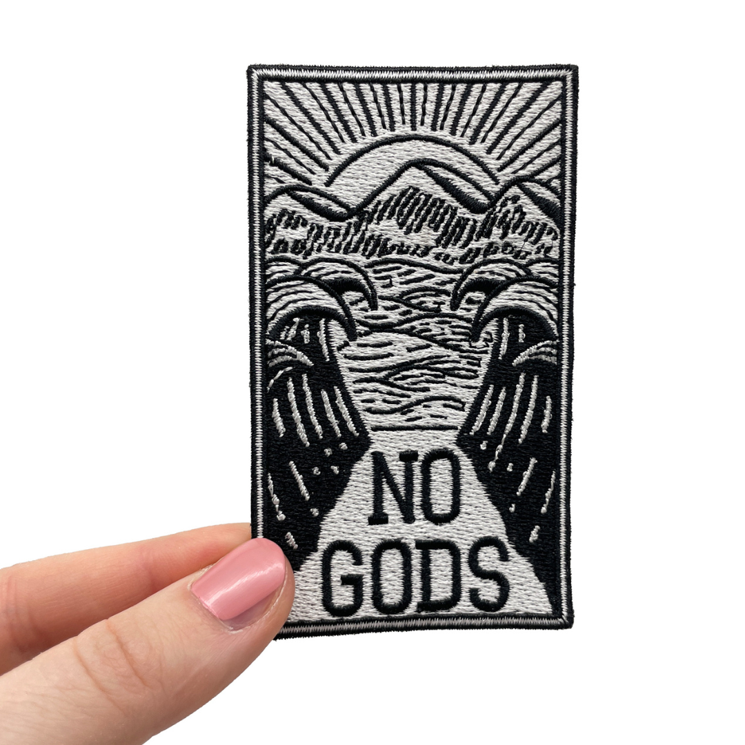 Frauenhand hält den No Gods Patch