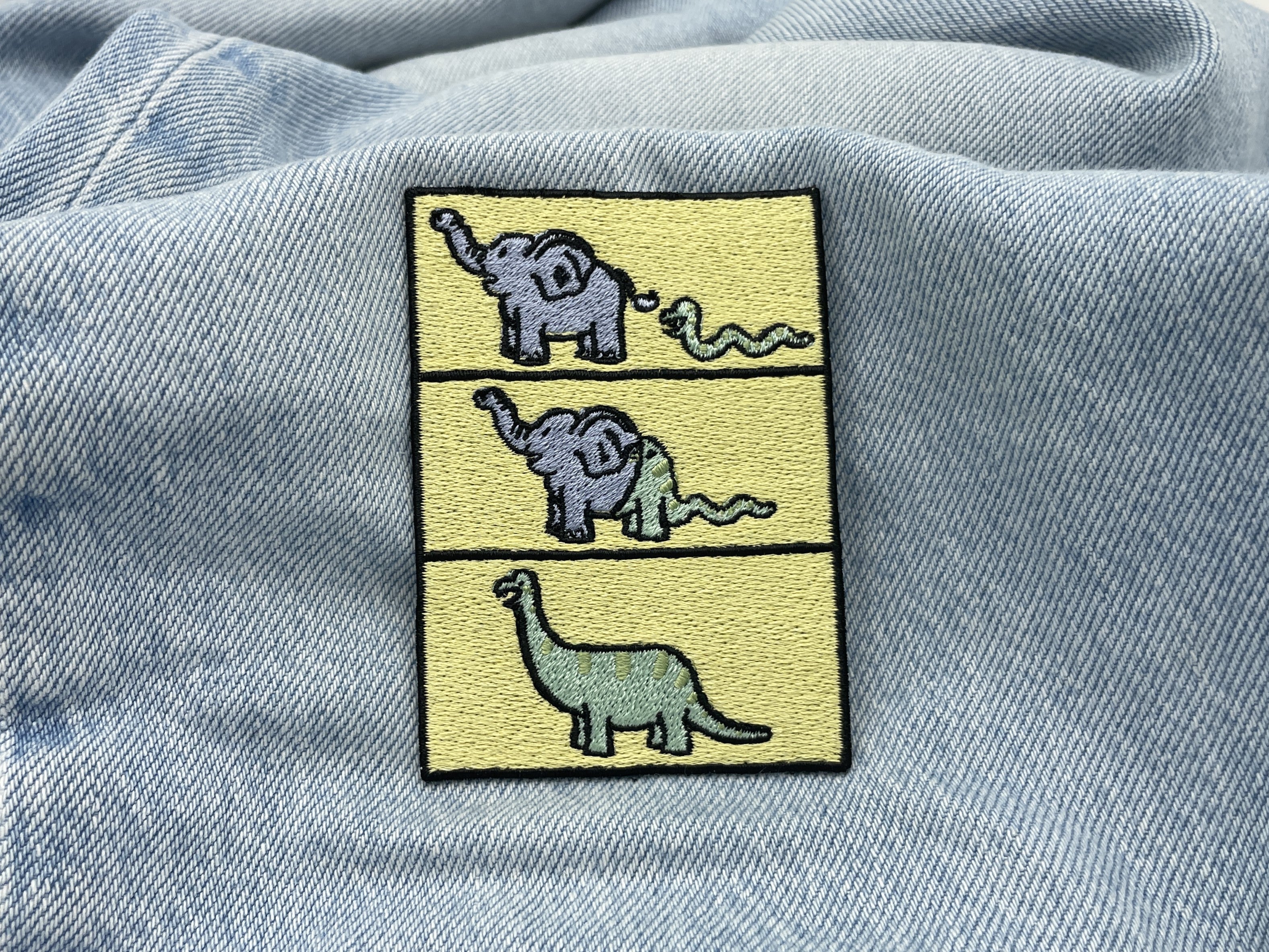 Dino Evolution Patch auf hellblauer Jeans