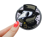 Frauenhand hält den Pest Doktor Patch 