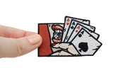 Frauenhand hält den 4 Asse Patch