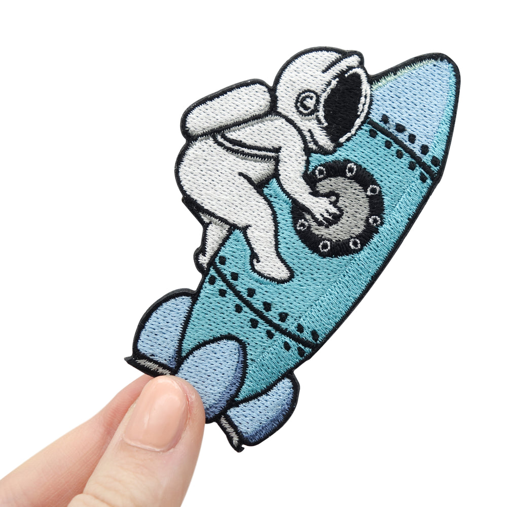 Frauenhand hält den Astronaut auf Rakete Patch 