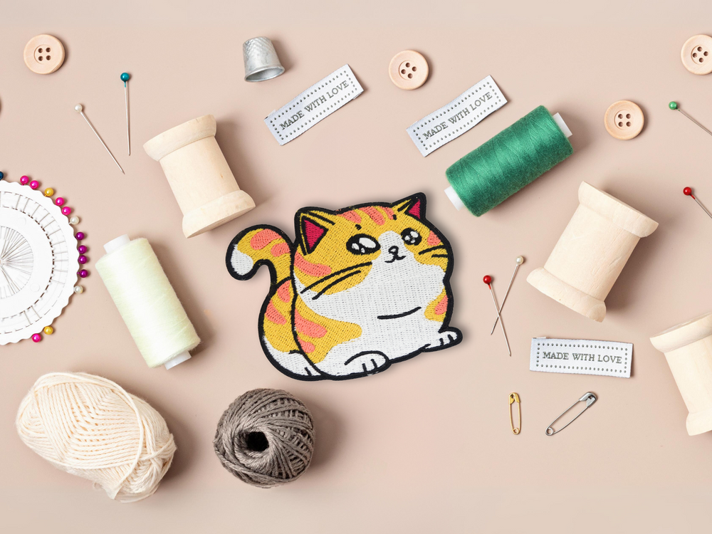 Dicke Katze Patch mit Nähzeug im Hintergrund