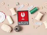 Fragile Patch mit Nähzeug im Hintergrund