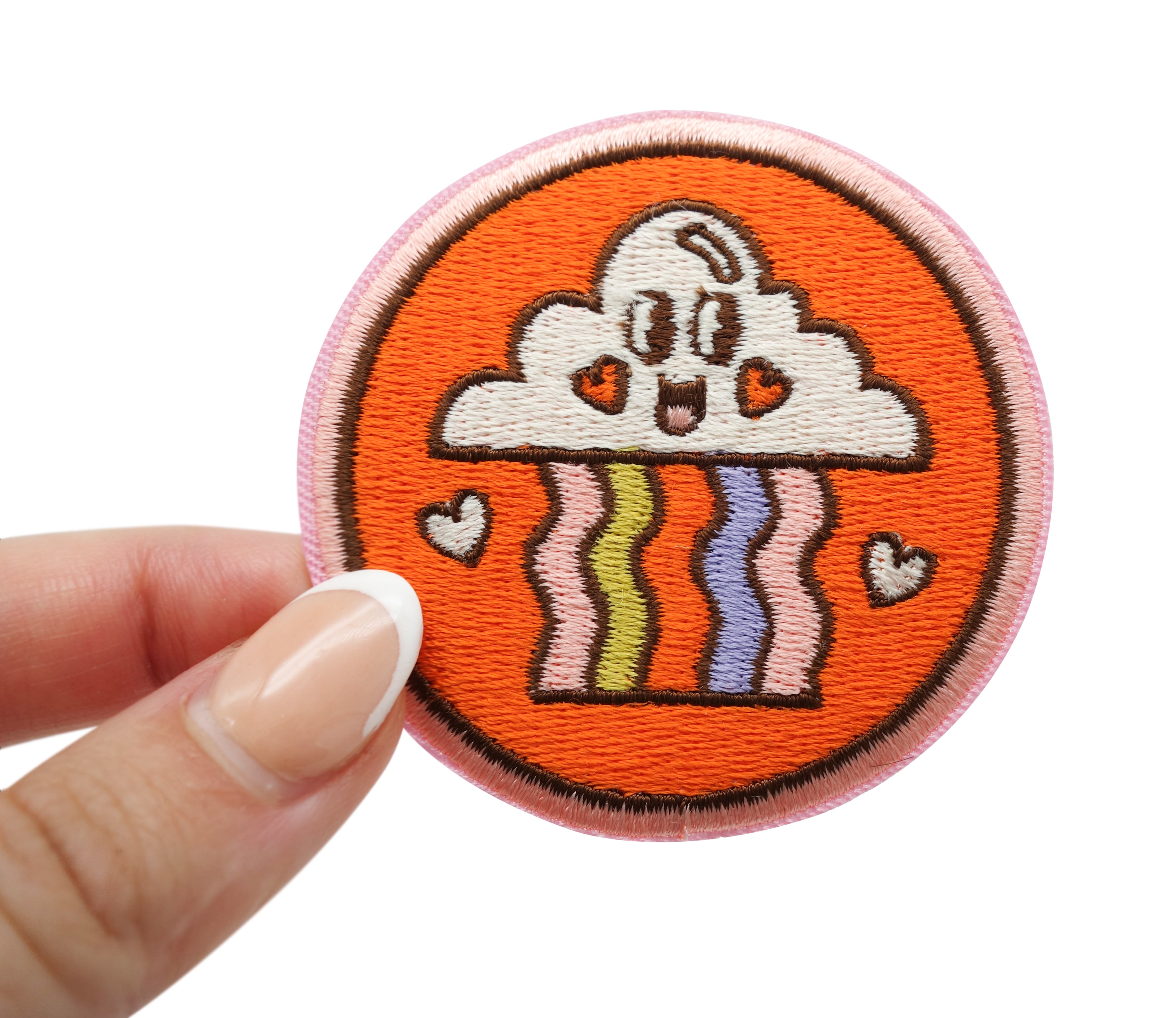 Frauenhand hält den Regenbogen Patch