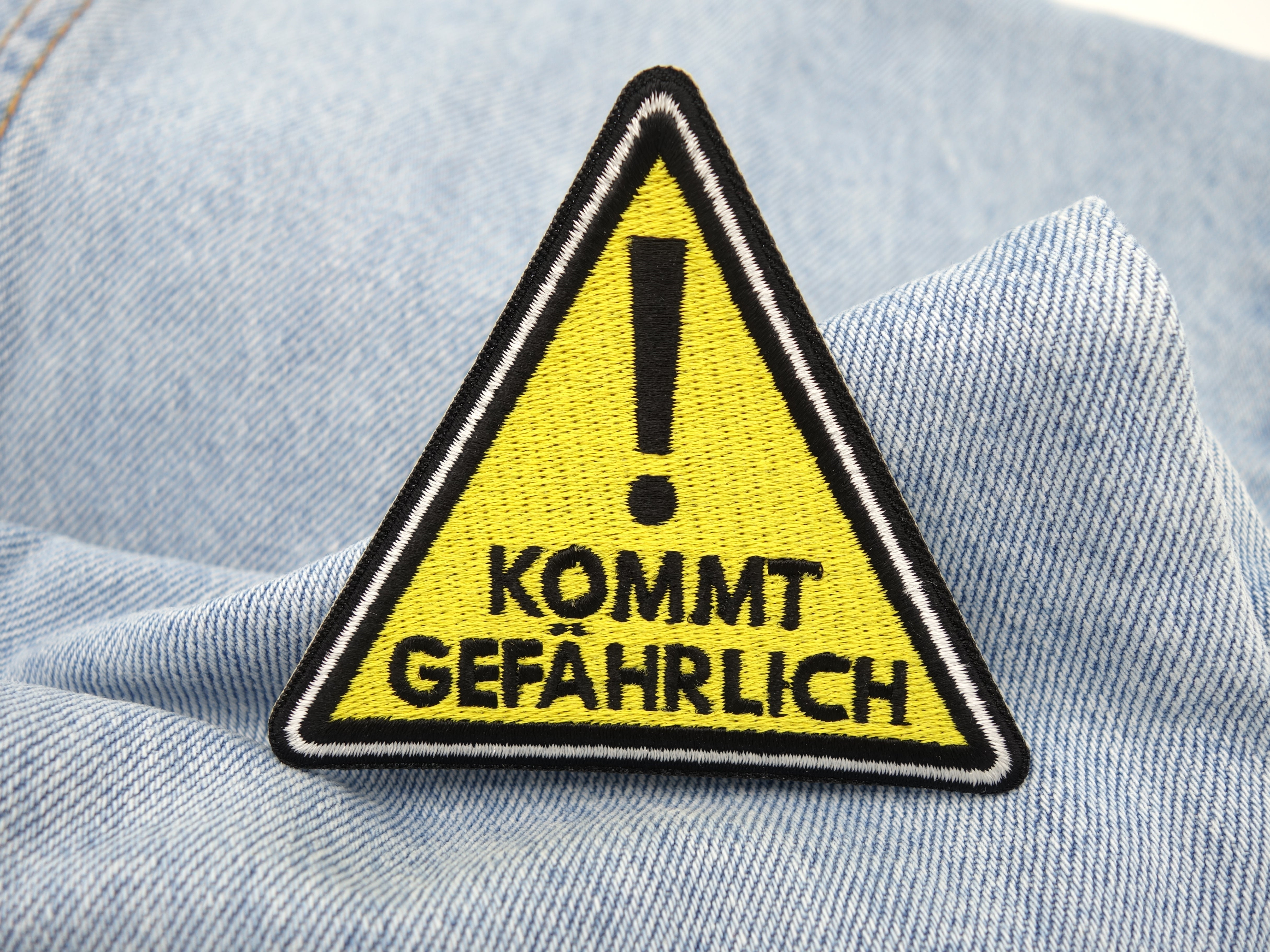 Kommt Gefährlich Patch auf hellblauer Jeans