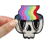 Frauenhand hält den Regenbogen im Totenkopf Patch