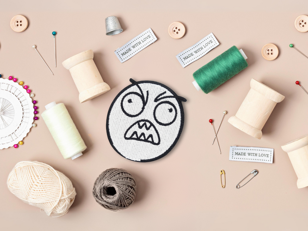 Grimasse Patch mit Nähzeug im Hintergrund
