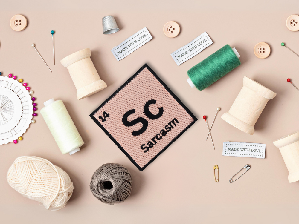 Sarcasm Patch mit Nähzeug im Hintergrund