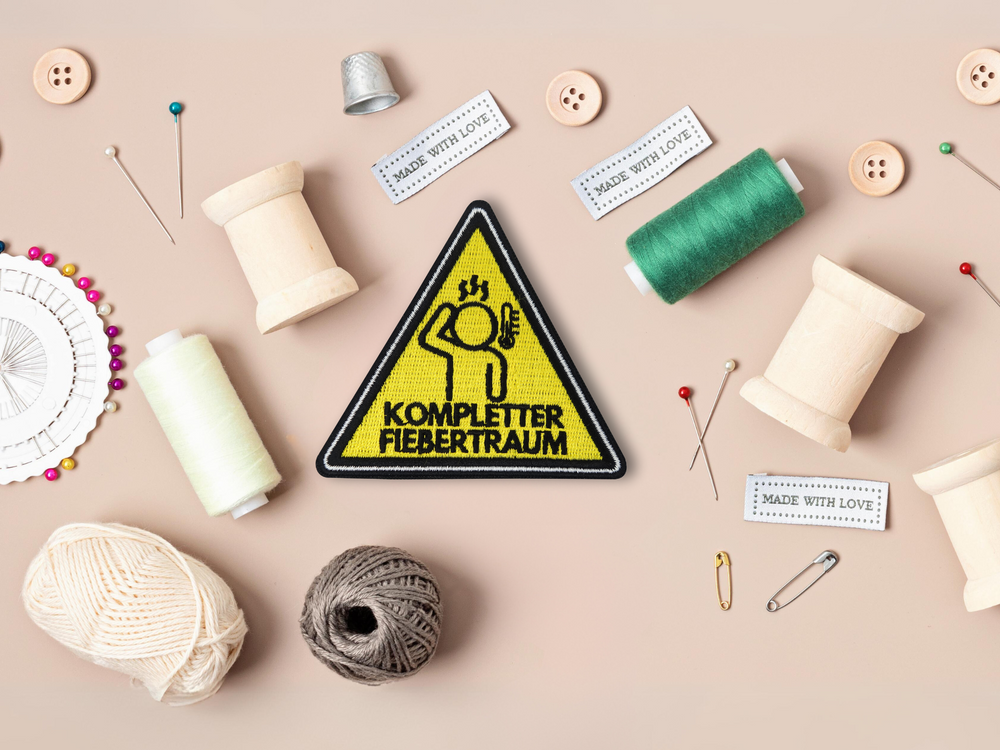 Fiebertraum Patch mit Nähzeug im Hintergrund