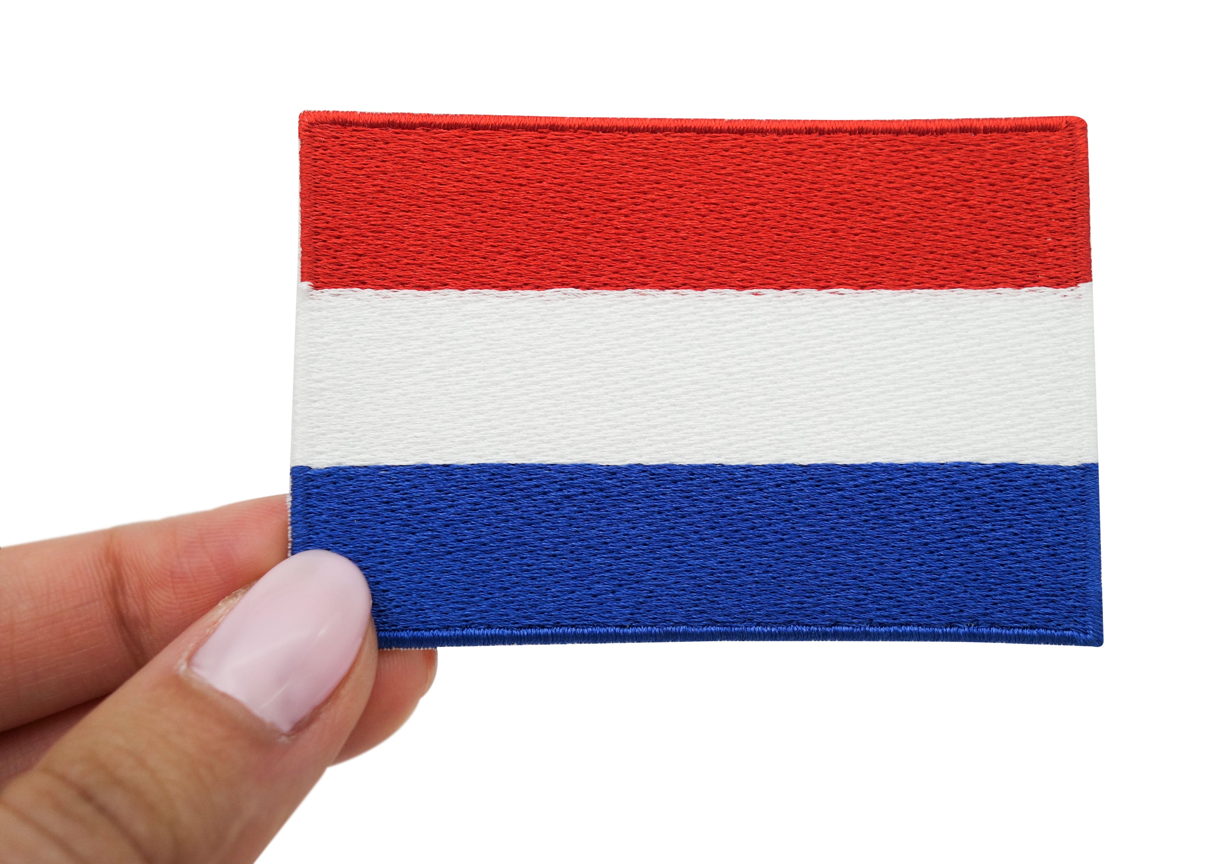 Frauenhand hält den Niederlande Flagge Patch